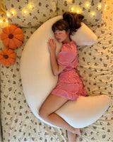 Cream crescent body pillow shown on a bed