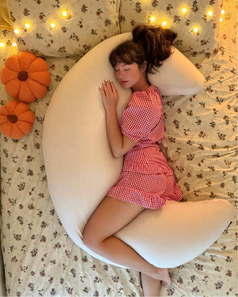 Cream crescent body pillow shown on a bed